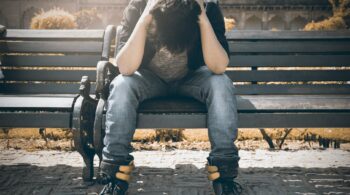 man in black shirt and gray denim pants sitting on gray padded bench