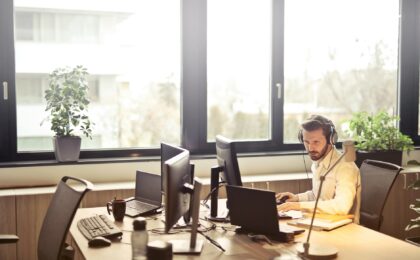 man with headphones facing computer monitor